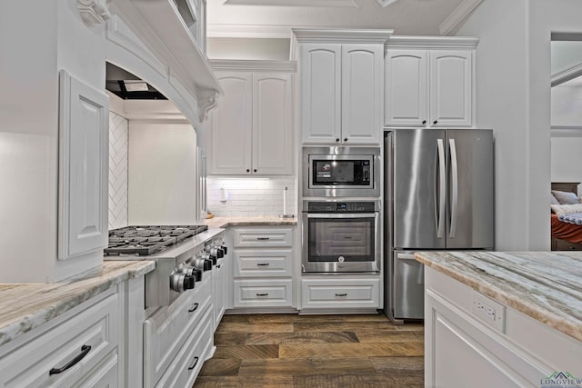 kitchen featuring white cabinets, appliances with stainless steel finishes, light stone counters, and decorative backsplash