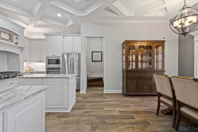 kitchen with appliances with stainless steel finishes, light stone countertops, decorative light fixtures, white cabinetry, and an inviting chandelier