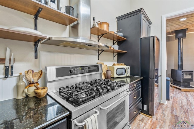 280 S Stonewall St, Tatum, TX 75691 - kitchen featuring stainless steel appliances, open shelves, island range hood, dark stone countertops, and light wood-style flooring