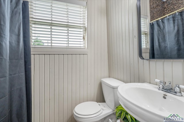 280 S Stonewall St, Tatum, TX 75691 - full bathroom featuring a sink, toilet, a shower with curtain, and wooden walls
