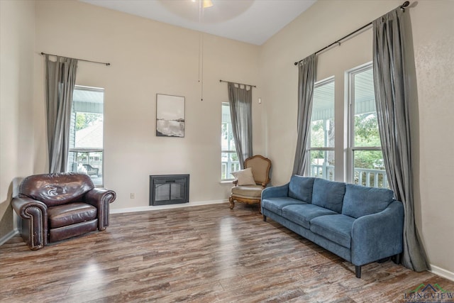 280 S Stonewall St, Tatum, TX 75691 - living area with wood finished floors, a glass covered fireplace, ceiling fan, and baseboards