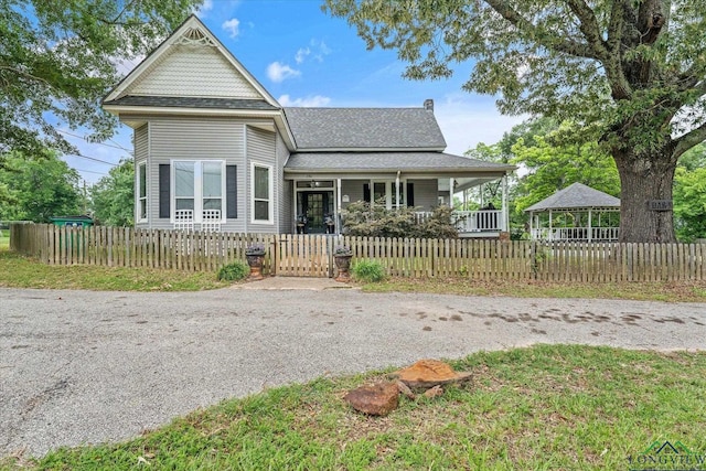 280 S Stonewall St, Tatum, TX 75691 - victorian-style house with a porch, a shingled roof, a fenced front yard, and a gate
