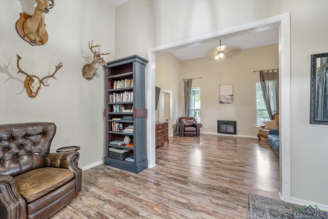 280 S Stonewall St, Tatum, TX 75691 - living area with wood finished floors, a towering ceiling, baseboards, and a glass covered fireplace