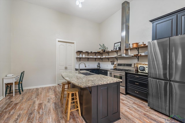 280 S Stonewall St, Tatum, TX 75691 - kitchen featuring stainless steel appliances, a sink, a breakfast bar area, light wood-style floors, and light stone countertops