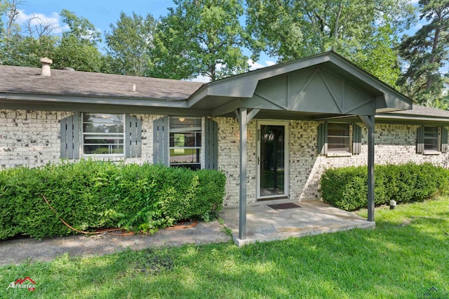 711 Comer St, Carthage, TX 75633 - view of front of home with a front yard, brick siding, and a patio area