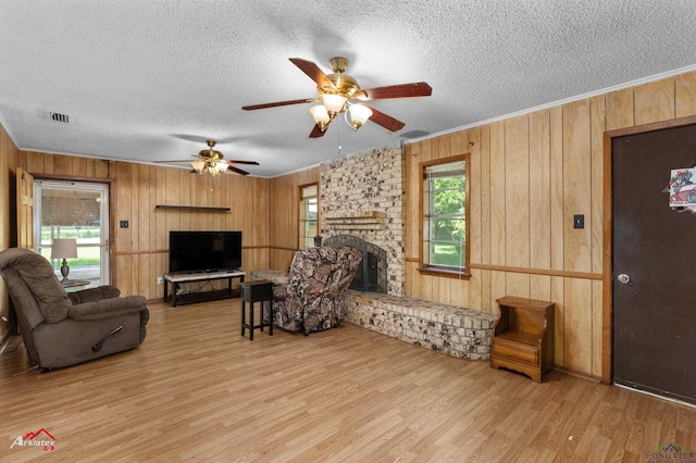 711 Comer St, Carthage, TX 75633 - living room featuring wood walls, wood finished floors, a textured ceiling, a fireplace, and a ceiling fan