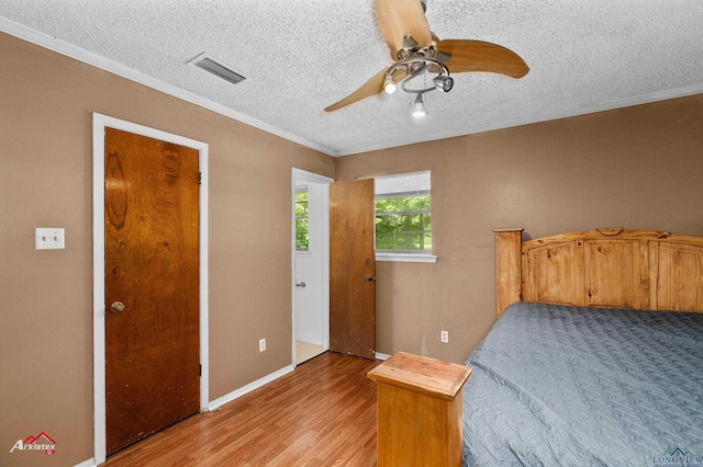 711 Comer St, Carthage, TX 75633 - bedroom with crown molding, light wood-style flooring, a textured ceiling, ceiling fan, and baseboards