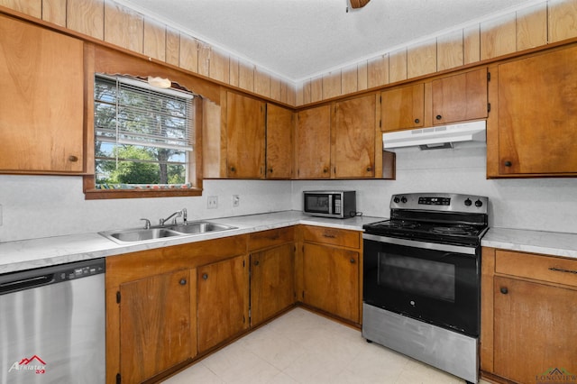711 Comer St, Carthage, TX 75633 - kitchen featuring under cabinet range hood, appliances with stainless steel finishes, a sink, light countertops, and brown cabinets
