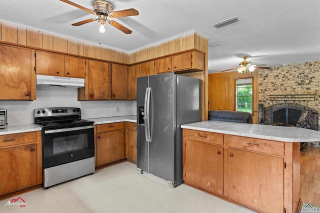 711 Comer St, Carthage, TX 75633 - kitchen with stainless steel appliances, under cabinet range hood, ceiling fan, brown cabinets, and a textured ceiling