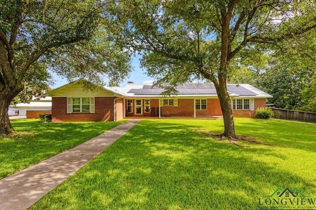 ranch-style home with a front lawn and solar panels