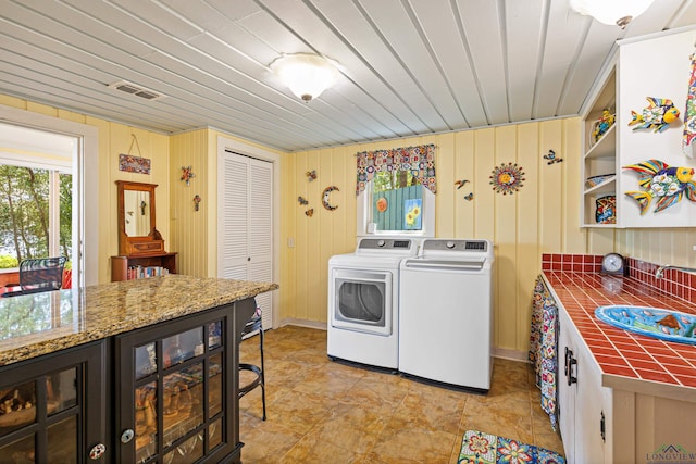 laundry area featuring washing machine and clothes dryer, sink, wine cooler, wood walls, and wood ceiling