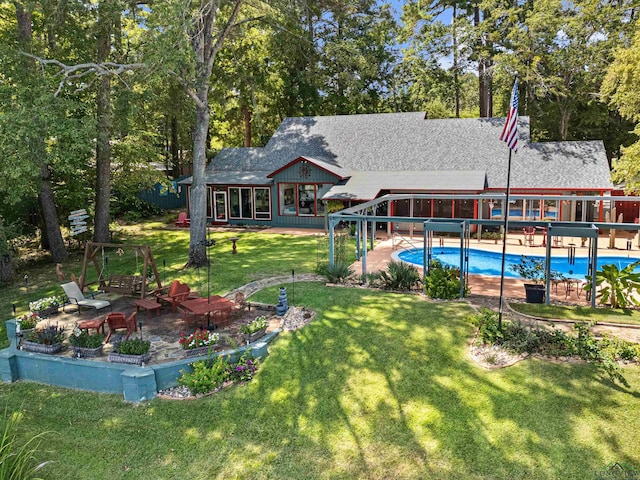 rear view of property featuring a sunroom, a yard, a patio, and an outdoor fire pit