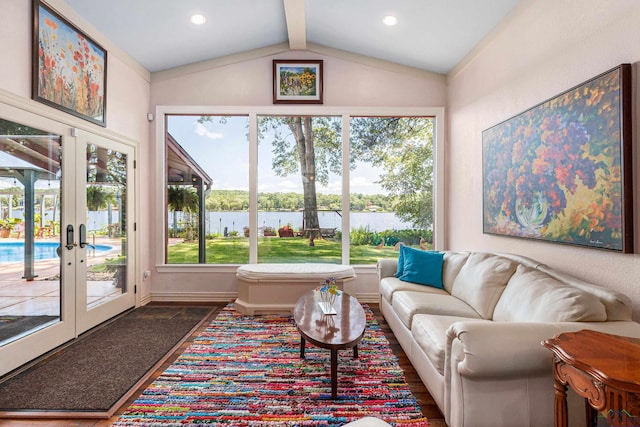 living room featuring french doors, vaulted ceiling with beams, and a water view