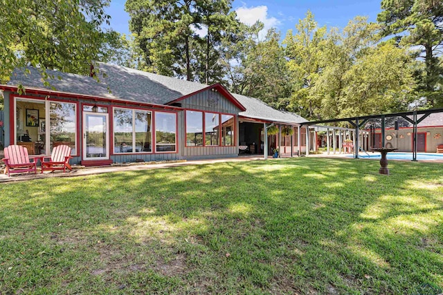 back of property featuring a yard, a pool, and a sunroom