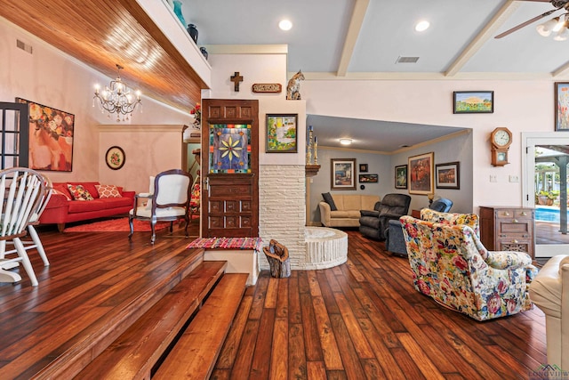 living room with lofted ceiling with beams, wood-type flooring, a fireplace, and ceiling fan with notable chandelier