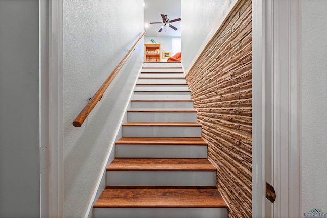 stairs featuring ceiling fan