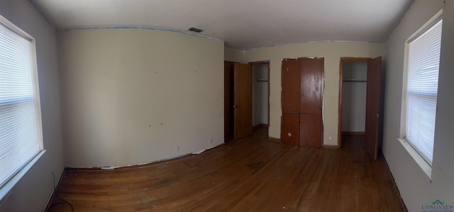 unfurnished bedroom featuring multiple windows and dark hardwood / wood-style flooring