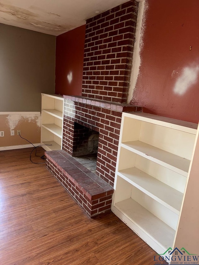 unfurnished living room featuring wood-type flooring, built in shelves, and a fireplace