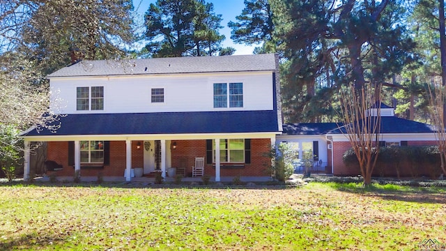 view of front facade featuring brick siding, covered porch, and a front lawn