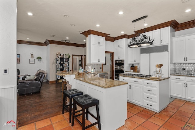 kitchen with a kitchen bar, appliances with stainless steel finishes, dark stone counters, sink, and white cabinets