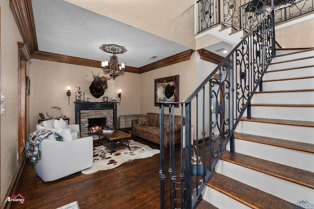 living room with ornamental molding, a textured ceiling, a fireplace, wood-type flooring, and a chandelier