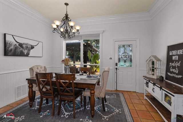 tiled dining room featuring ornamental molding and an inviting chandelier