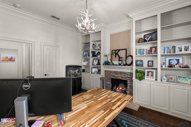 office space with dark wood-type flooring, crown molding, built in features, a notable chandelier, and a fireplace