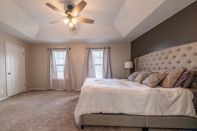 bedroom featuring carpet flooring, a tray ceiling, and ceiling fan