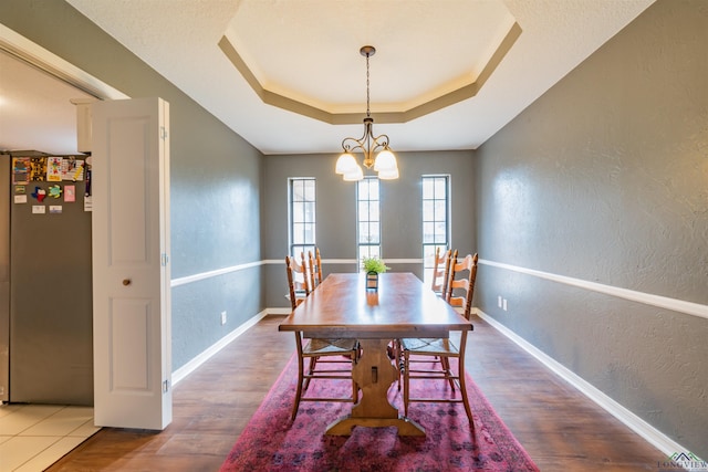 dining area featuring a chandelier, hardwood / wood-style floors, and a raised ceiling