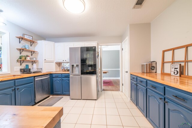 kitchen with white cabinetry, stainless steel appliances, blue cabinets, butcher block countertops, and light tile patterned floors