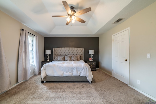 bedroom featuring ceiling fan, a raised ceiling, and light carpet