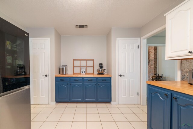 kitchen featuring white cabinetry, light tile patterned flooring, blue cabinets, and a textured ceiling