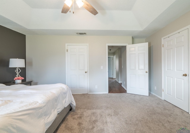 bedroom with a tray ceiling, ceiling fan, and carpet flooring