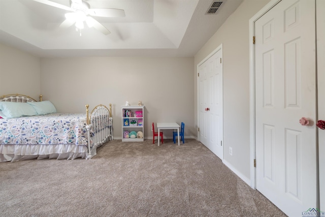 bedroom featuring carpet, a tray ceiling, and ceiling fan