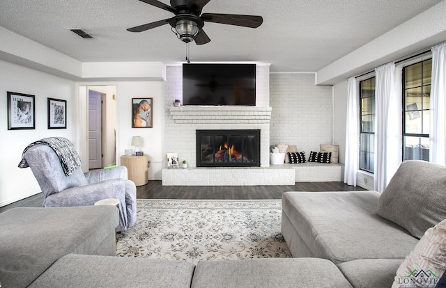 144 Hollie Cir, Sulphur Springs, TX 75482 - living room with wood finished floors, a fireplace, a ceiling fan, a textured ceiling, and baseboards