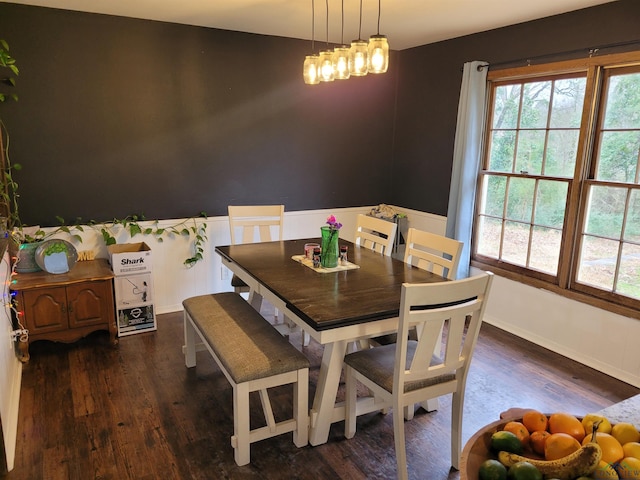 dining area featuring dark wood finished floors, wainscoting, and an inviting chandelier