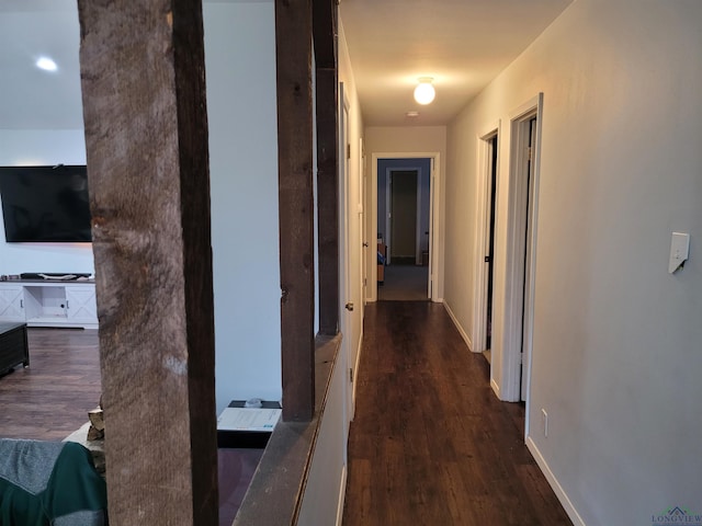 corridor with baseboards and dark wood-type flooring