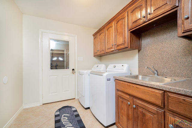 clothes washing area with cabinets, washing machine and clothes dryer, light tile patterned flooring, and sink