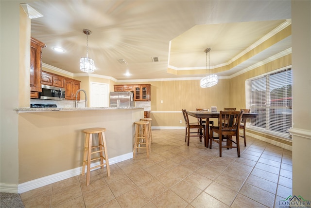 tiled dining area with ornamental molding, sink, and a tray ceiling