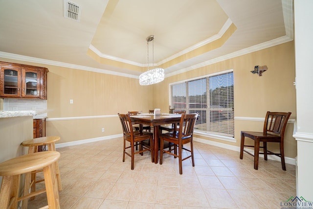 dining space with crown molding, a raised ceiling, and light tile patterned flooring