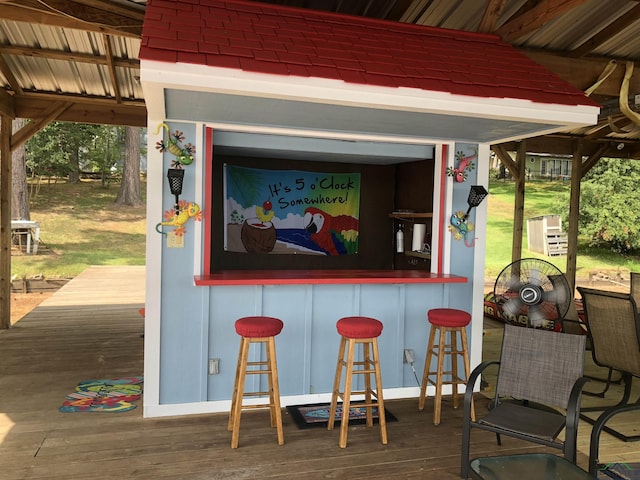 bar with a bar, wood finished floors, and a wealth of natural light