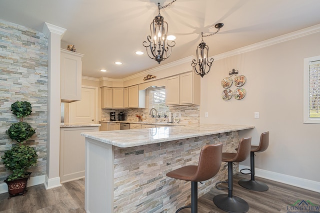 kitchen featuring a peninsula, dark wood-type flooring, a kitchen bar, crown molding, and tasteful backsplash