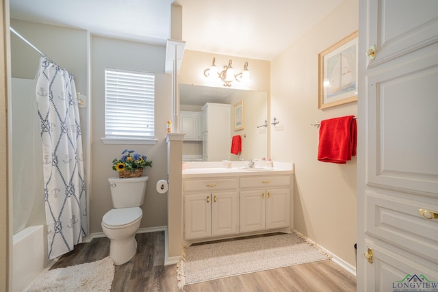 bathroom featuring baseboards, toilet, wood finished floors, vanity, and shower / bathtub combination with curtain