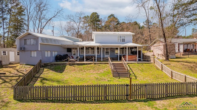 rear view of house featuring metal roof, a lawn, and a fenced backyard