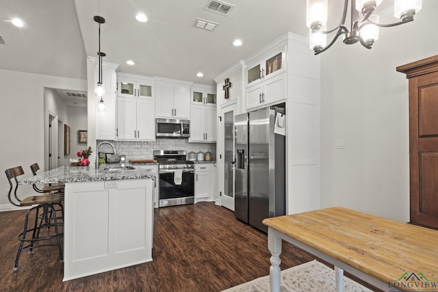 kitchen featuring light stone countertops, appliances with stainless steel finishes, decorative light fixtures, an inviting chandelier, and white cabinetry