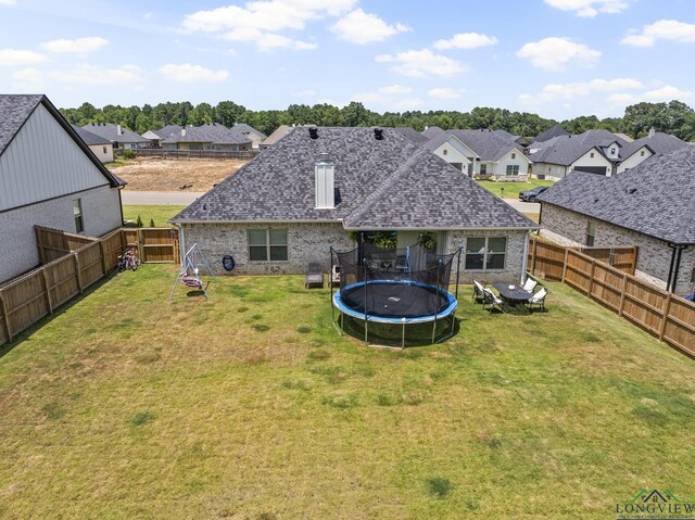 rear view of house featuring a lawn and a trampoline