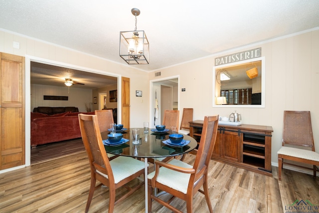 dining room with a notable chandelier, crown molding, and light wood-type flooring