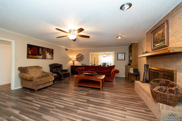 living area featuring a brick fireplace, a textured ceiling, a ceiling fan, and wood finished floors