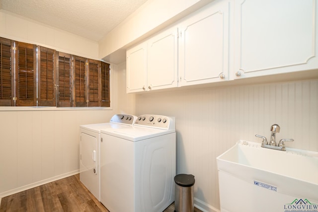 laundry room with sink, dark wood-type flooring, cabinets, independent washer and dryer, and a textured ceiling