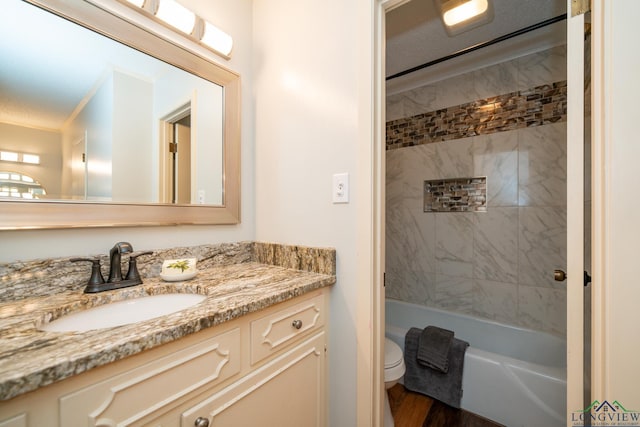 full bathroom with wood-type flooring, tiled shower / bath combo, vanity, ornamental molding, and toilet